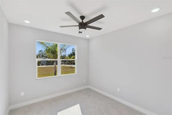 an empty room with ceiling fan and window