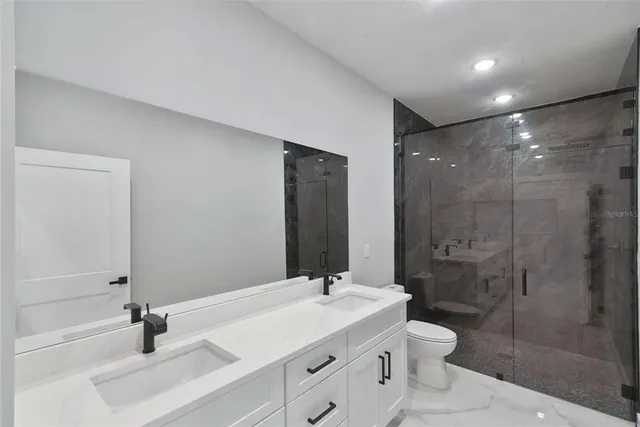 a bathroom with a sink a toilet a mirror and shower