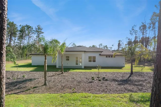 a view of a house with a yard and a large tree