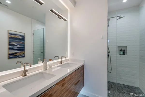 a bathroom with a double vanity sink mirror and shower