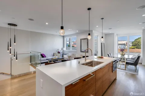 a kitchen with a stove a refrigerator a sink a dining table and chairs with wooden floor