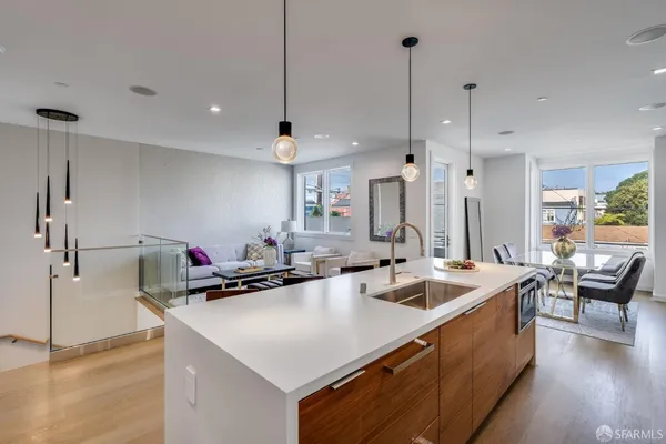 a kitchen with a stove a refrigerator a sink a dining table and chairs with wooden floor
