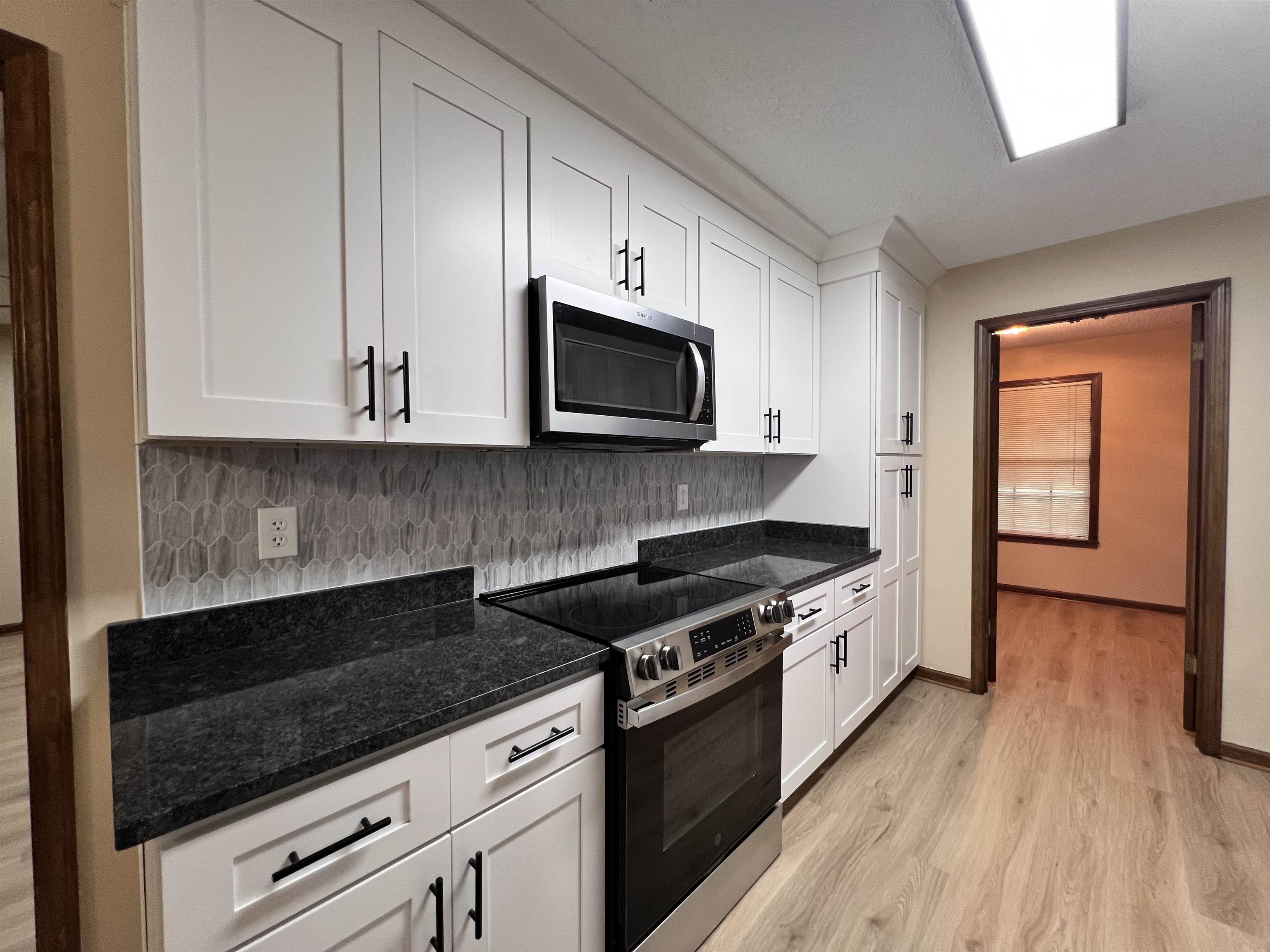 309 West Powell Road Collierville, TN 38017 - Photo 5 of 40 a kitchen with granite countertop a stove a microwave and wooden cabinets