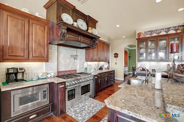 a kitchen with stainless steel appliances granite countertop a stove a sink dishwasher and cabinets with wooden floor