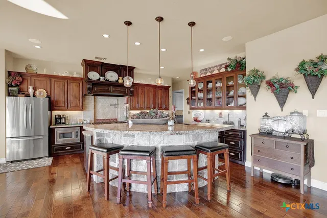 a kitchen with stainless steel appliances granite countertop a table chairs stove and wooden floor