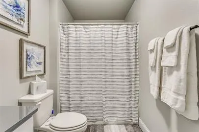 a bathroom with a toilet and a shower curtain
