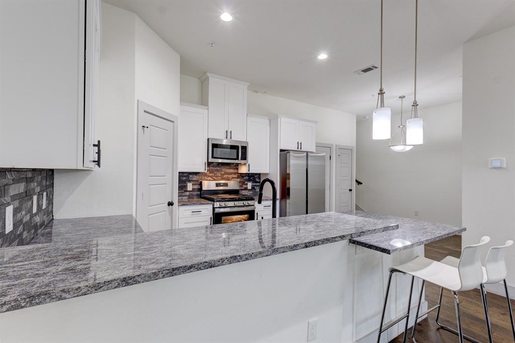 6043 Rivendell Drive Frisco, TX 75035 - Photo 19 of 38 a kitchen with stainless steel appliances a sink a stove a refrigerator cabinets and chairs