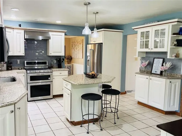 a kitchen with stainless steel appliances kitchen island granite countertop a stove a sink and a refrigerator