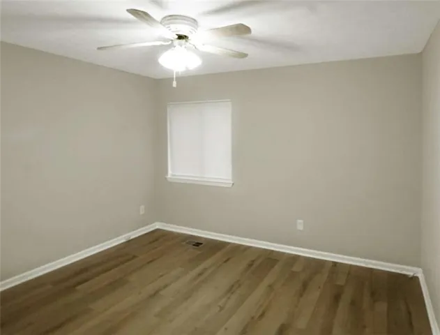 a view of a room with wooden floor and a ceiling fan