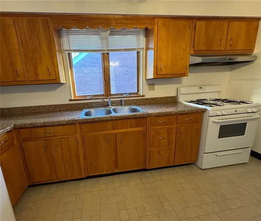 a kitchen with granite countertop a sink a stove and cabinets