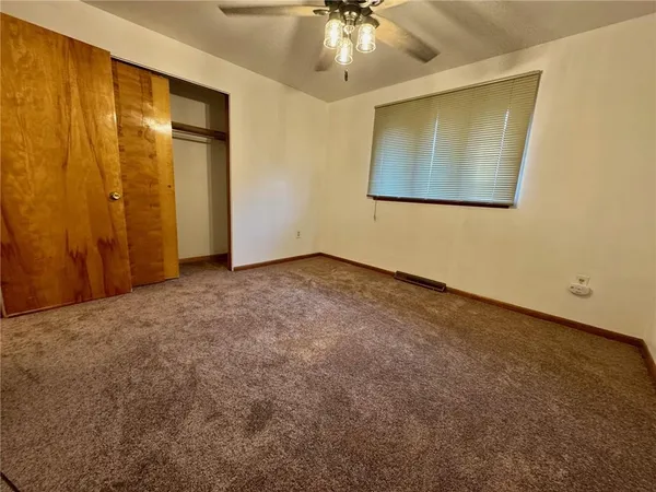 a view of an empty room with a chandelier fan
