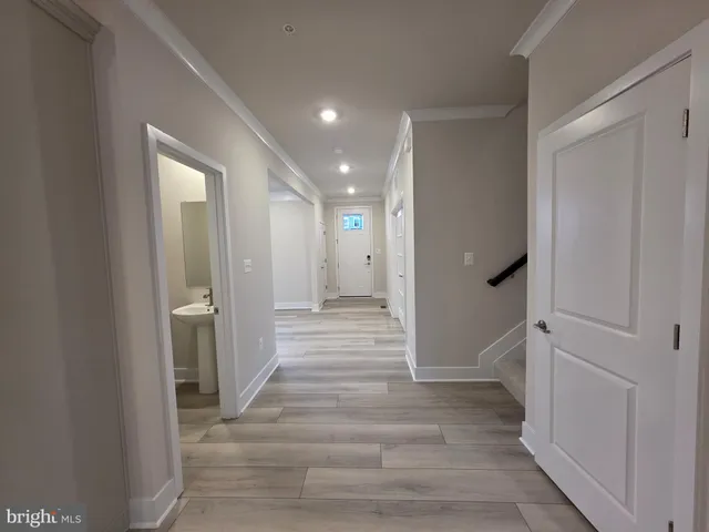 a view of a hallway with wooden floor and a bathroom
