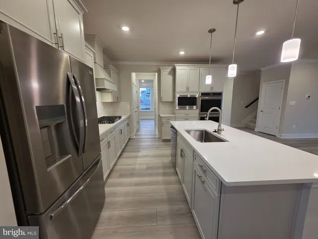 a large kitchen with a large center island wooden floor and stainless steel appliances