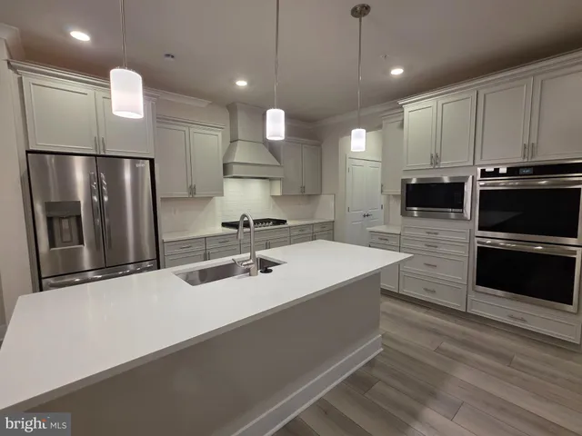 a large kitchen with a large counter top stainless steel appliances and cabinets