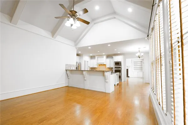 a view of an empty room with window and wooden floor
