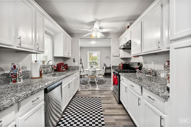 a kitchen with granite countertop a sink stove top oven and cabinets