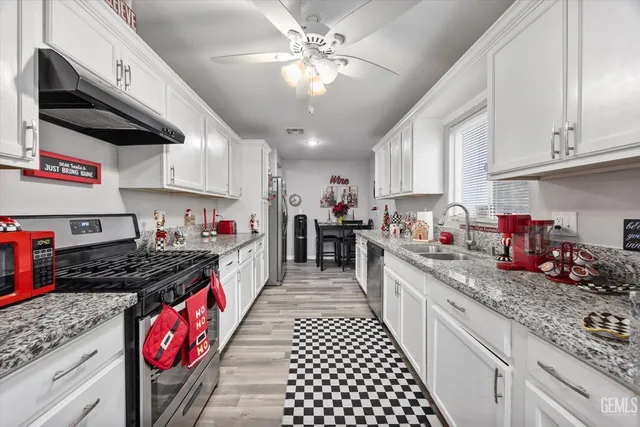 a kitchen with stainless steel appliances granite countertop a stove a sink dishwasher and cabinets with wooden floor