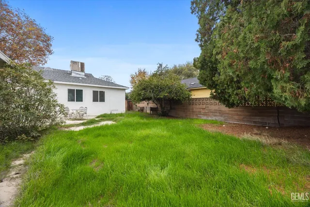 a backyard of a house with plants and large trees