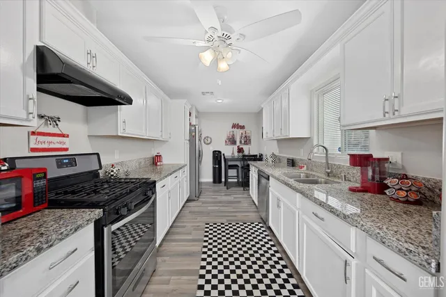 a kitchen with stainless steel appliances granite countertop a sink stove and cabinets