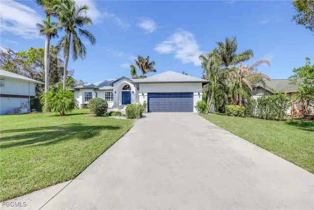 a front view of a house with a yard and palm trees