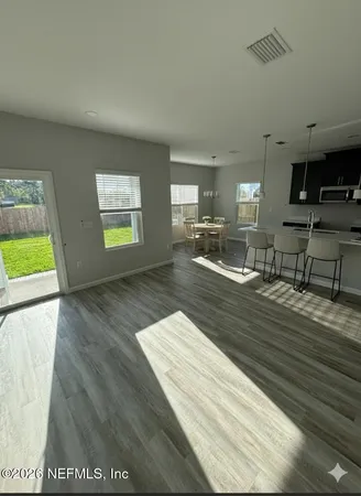 a view of kitchen and empty room with wooden floor