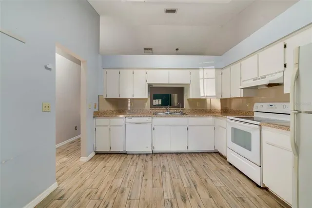 a kitchen with granite countertop white cabinets and white appliances