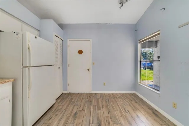 a view of an empty room with window and wooden floor
