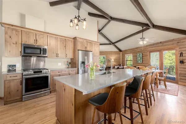 a kitchen with stainless steel appliances granite countertop a stove top oven a sink a dining table and chairs with wooden floor
