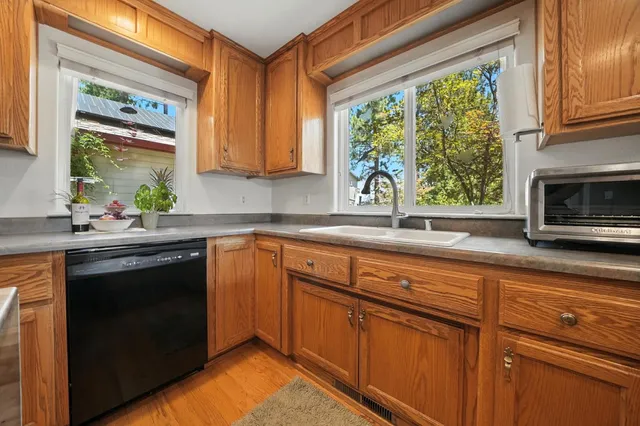 a kitchen with stainless steel appliances granite countertop a refrigerator a sink dishwasher and wooden cabinets with wooden floor