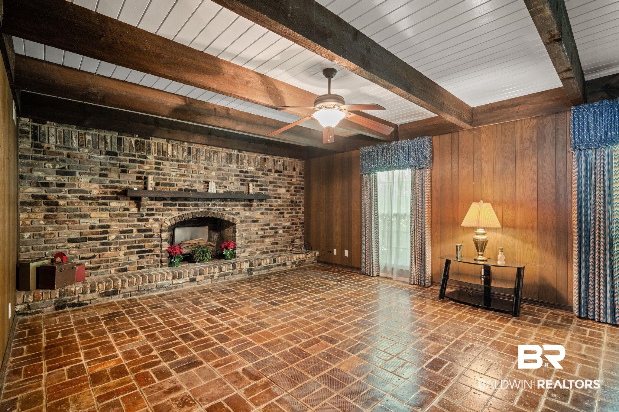 950 Walter Smith Road Mobile, AL 36695 - Photo 15 of 51 Unfurnished living room with wood walls, beam ceiling, brick flooring, a ceiling fan, and a fireplace