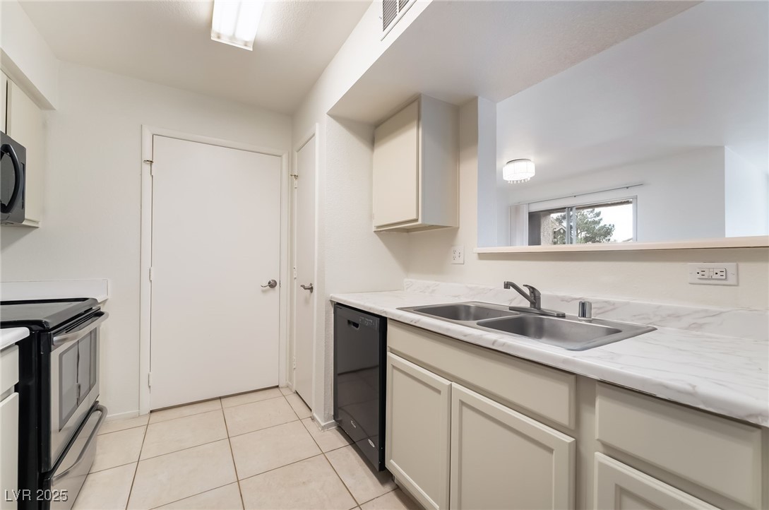 8101 West Flamingo Road, Unit 1090 Las Vegas, NV 89147 - Photo 11 of 30 Kitchen featuring light countertops, black appliances, light tile patterned floors, and white cabinetry