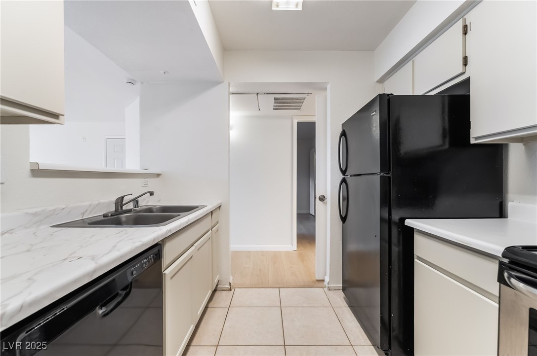 8101 West Flamingo Road, Unit 1090 Las Vegas, NV 89147 - Photo 14 of 30 Kitchen featuring light countertops, black appliances, white cabinetry, and light tile patterned flooring