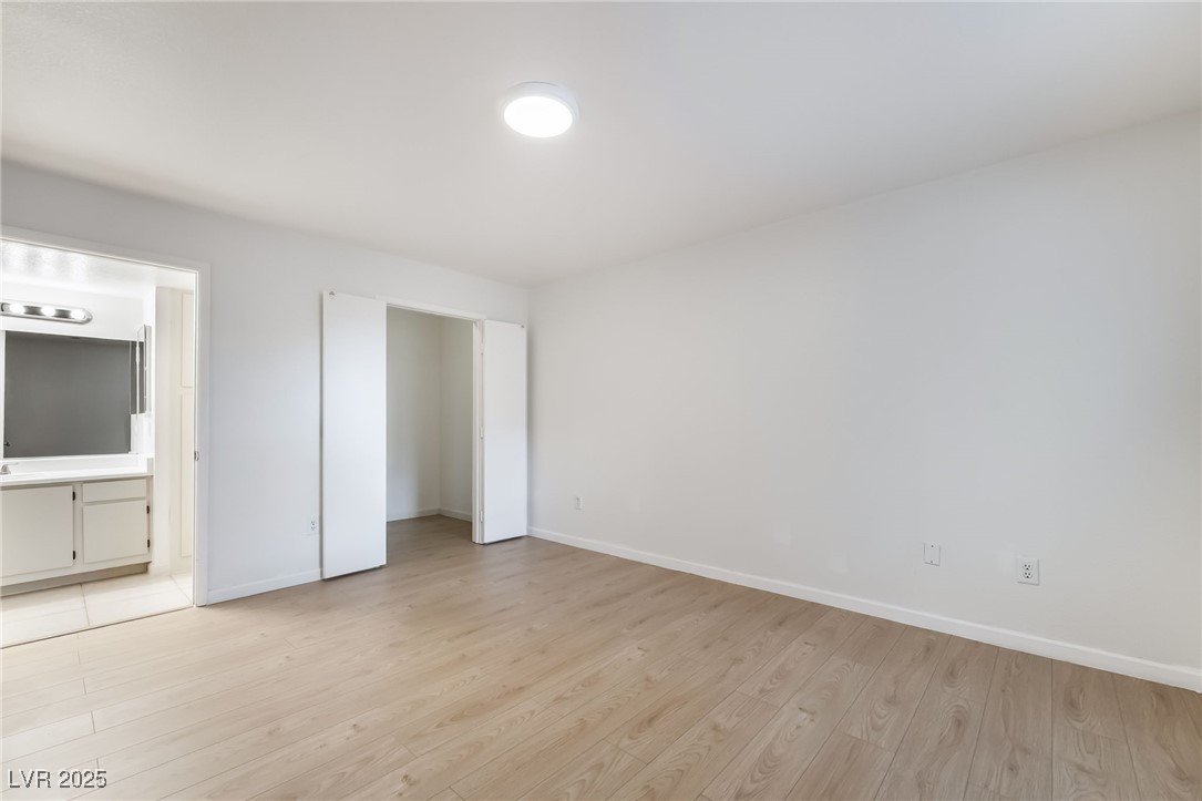 8101 West Flamingo Road, Unit 1090 Las Vegas, NV 89147 - Photo 15 of 30 Unfurnished bedroom with light wood-type flooring and ensuite bath