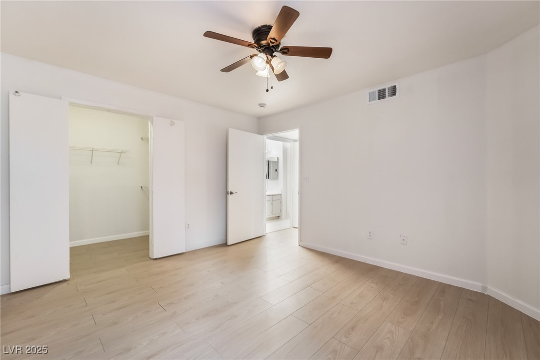 8101 West Flamingo Road, Unit 1090 Las Vegas, NV 89147 - Photo 21 of 30 Unfurnished bedroom with a walk in closet, light wood finished floors, and a ceiling fan