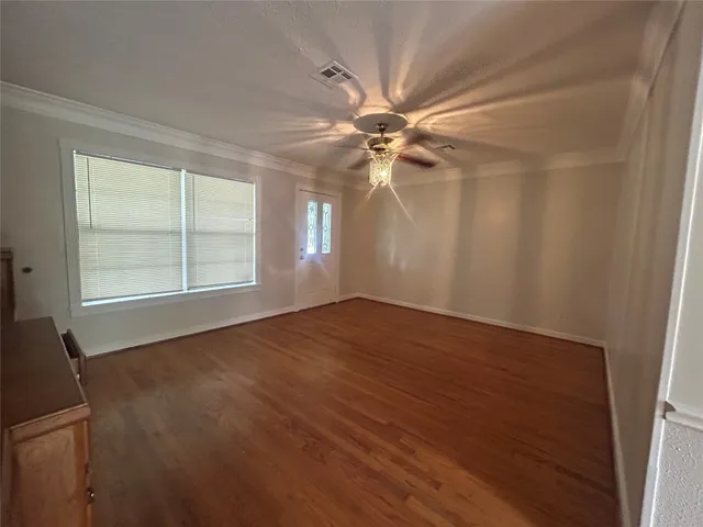 an empty room with wooden floor fan and windows