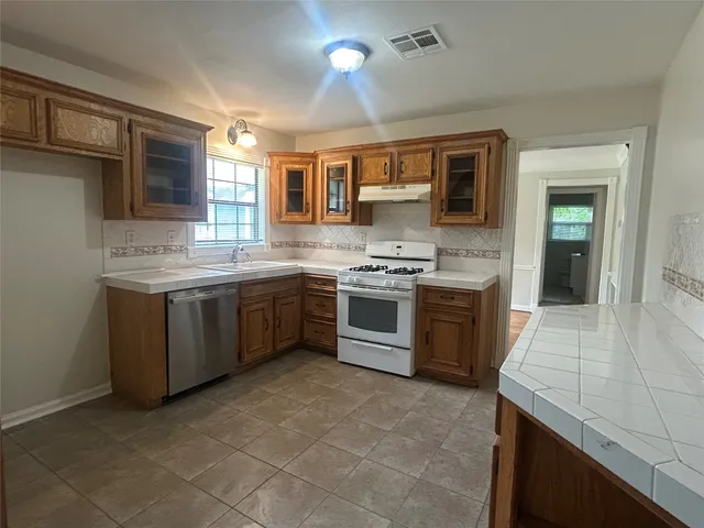 a kitchen with stainless steel appliances granite countertop a stove a sink and a refrigerator