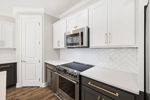 a kitchen with stainless steel appliances white cabinets and a stove top oven