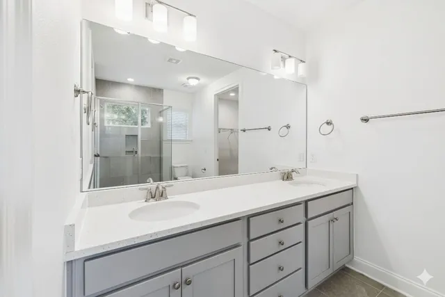 a bathroom with a sink double vanity granite tub shower and a mirror