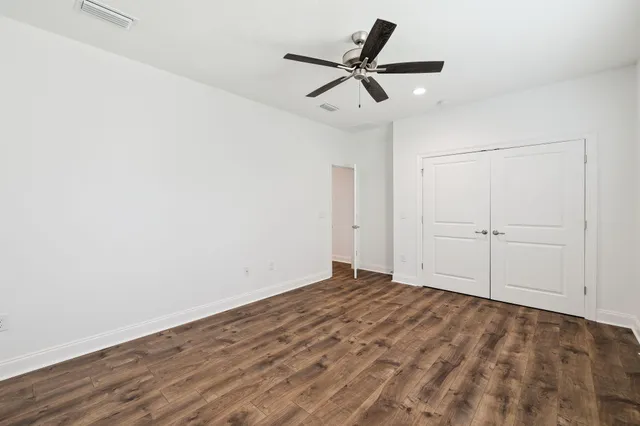 an empty room with a ceiling fan and wooden floor