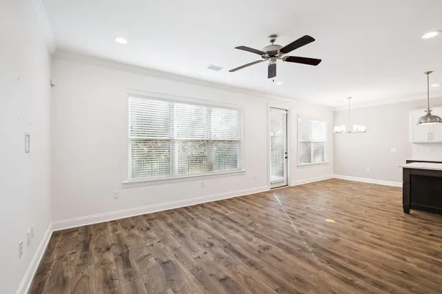 a view of empty room with wooden floor and ceiling fan