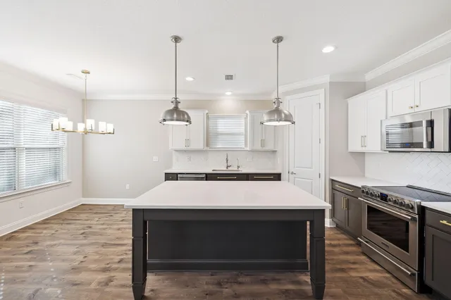 a kitchen with kitchen island a stove a sink and a wooden floor