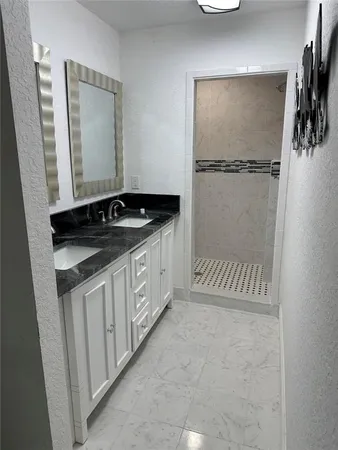 a bathroom with a granite countertop sink a mirror and a shower