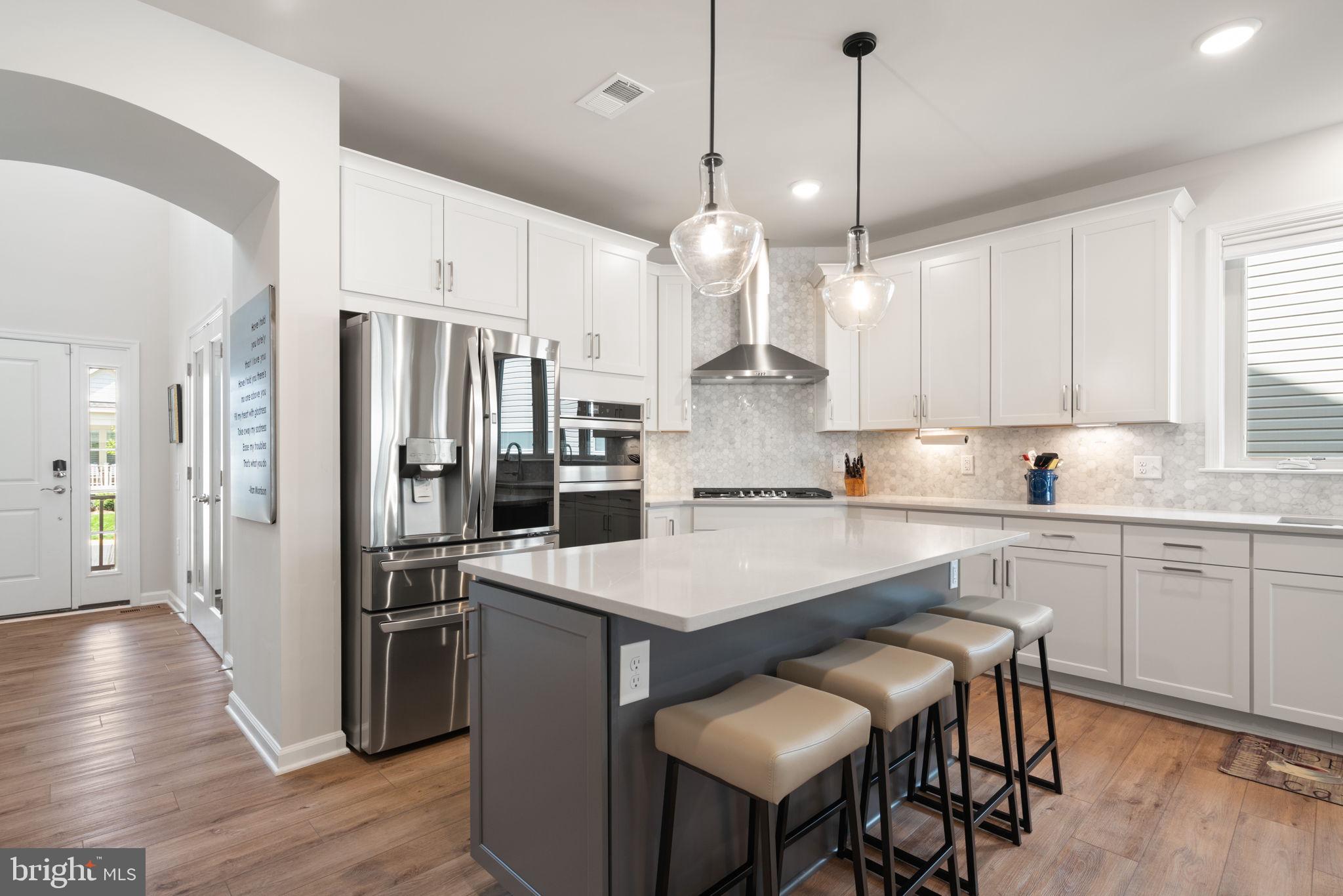 15795 Gardenia Rdg Way Haymarket, VA 20169 - Photo 6 of 63 a kitchen with stainless steel appliances granite countertop a refrigerator a sink dishwasher a stove a dining table and chairs with wooden floor