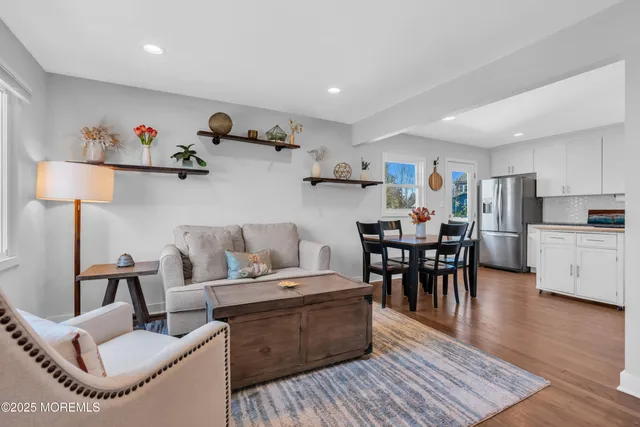 a living room with furniture and a dining table with wooden floor