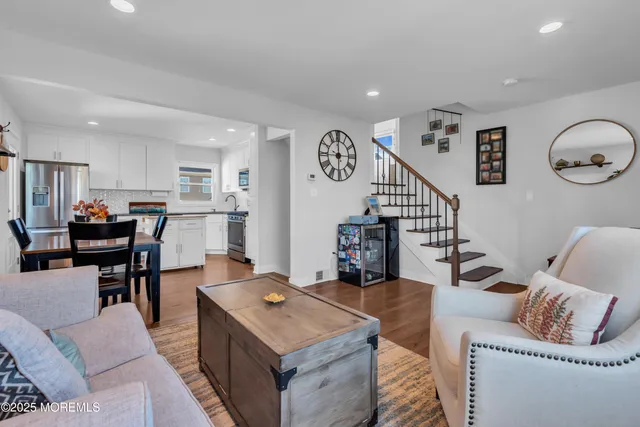 a living room with furniture kitchen view and a wooden floor