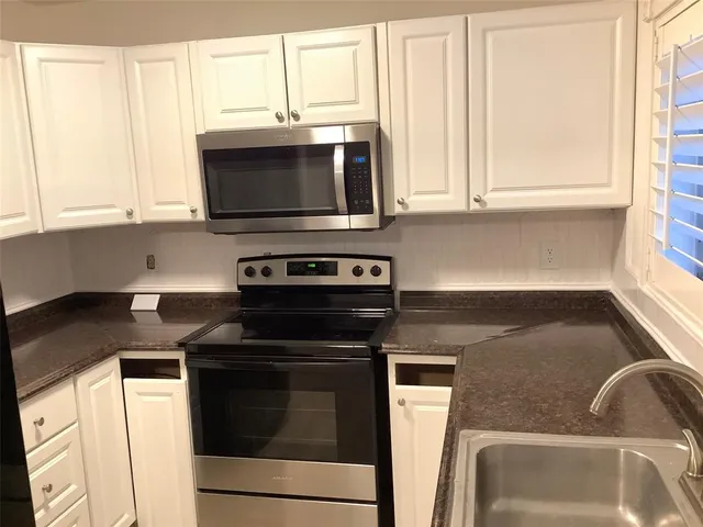 a white kitchen with granite countertop white cabinets and a sink