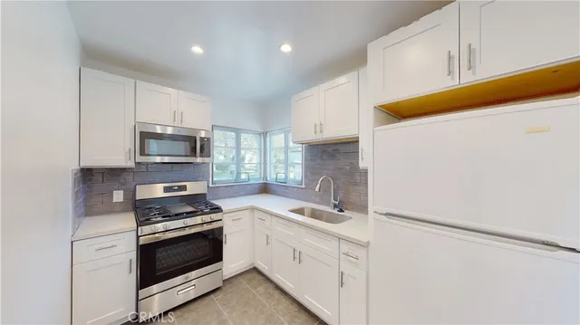 a kitchen with white cabinets and white appliances
