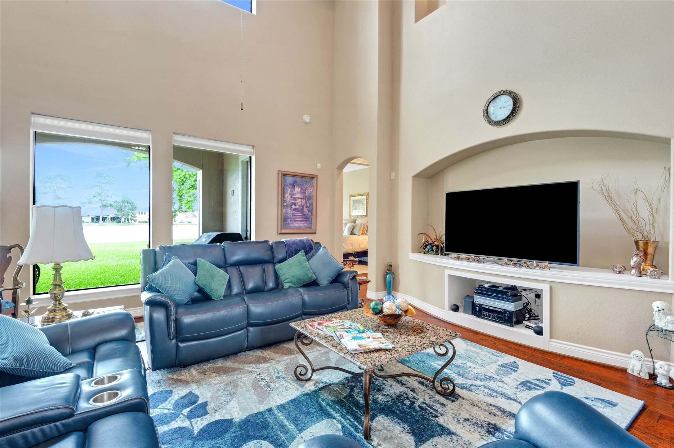 6119 Lofty Lane Spring, TX 77379 - Photo 16 of 40 Spacious family room with high ceilings and abundant natural light. Features include a large TV niche, elegant decor, and comfortable seating. Windows offer a picturesque view of the lake.