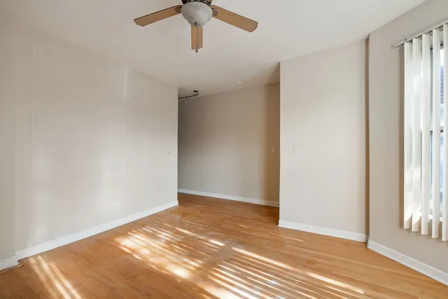 an empty room with wooden floor fan and windows