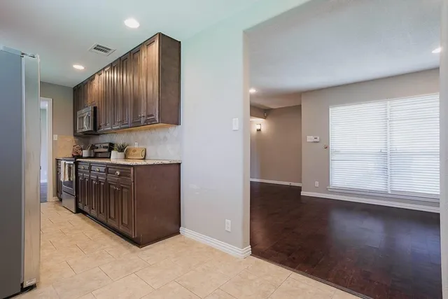 a kitchen with stainless steel appliances granite countertop a stove a sink and a refrigerator with wooden floor